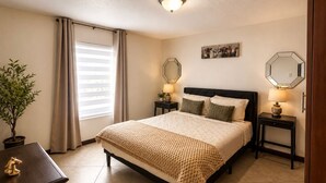 Une chambre à coucher avec un lit, des lampes de chevet, une plante en pot et une fenêtre avec des rideaux.