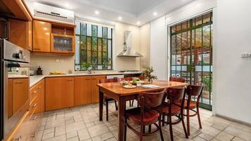 A modern kitchen with wooden cabinets, a dining table with chairs, and a large window with a view of the outdoors.