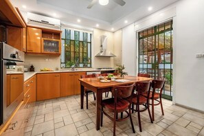 A modern kitchen with wooden cabinets, a dining table with chairs, and a large window with a view of the outdoors.