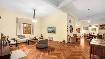 A spacious living area with a herringbone wood floor, a sofa, a coffee table, and a dining table with chairs.