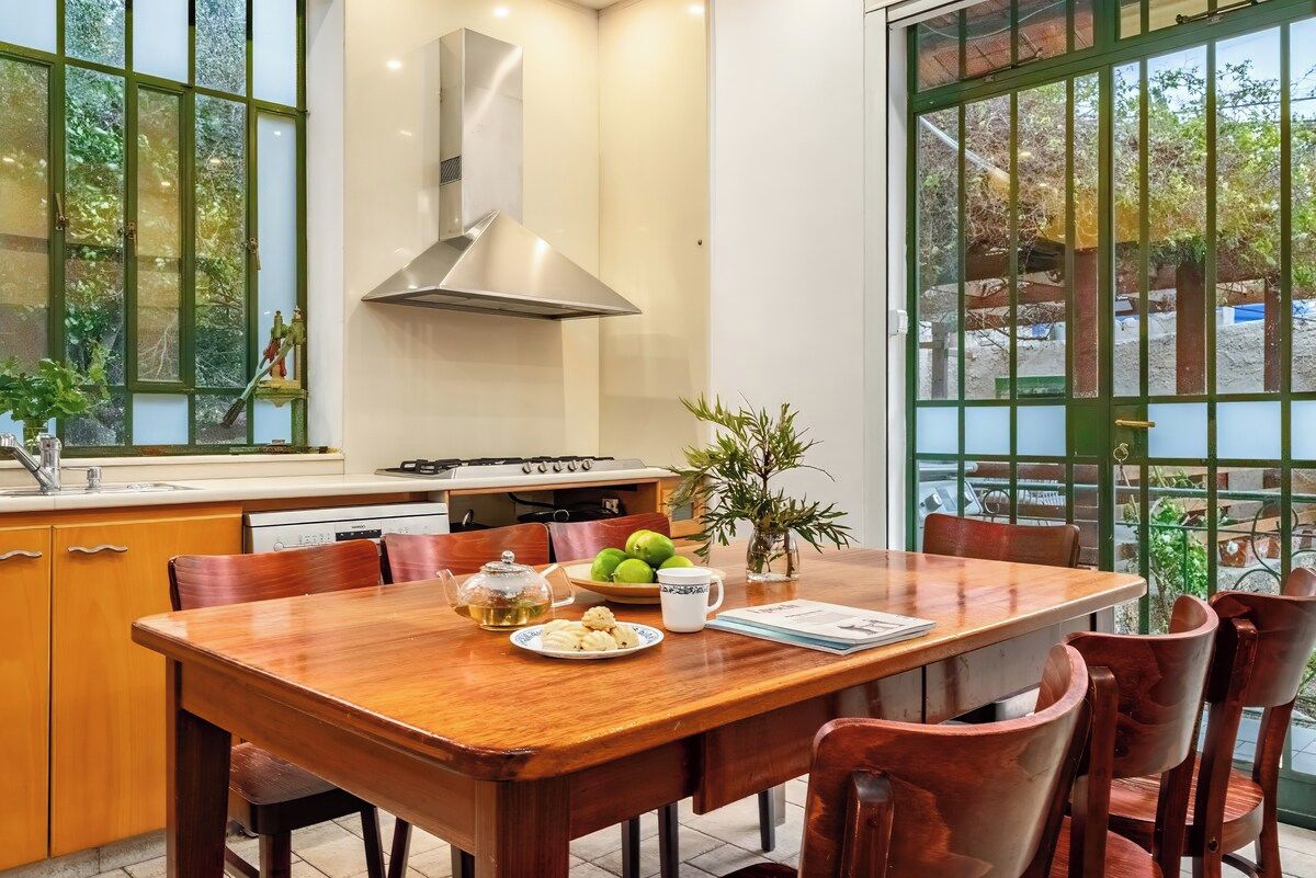 Un comedor con mesa de madera, sillas, estufa y ventana con vistas a la vegetación.