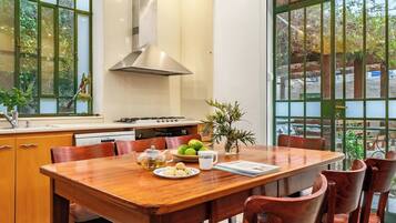 Un comedor con mesa de madera, sillas, estufa y ventana con vistas a la vegetación.