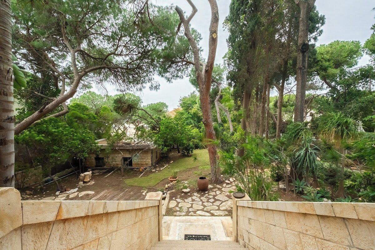 A stone staircase leading to a courtyard with a small building, surrounded by trees and greenery.