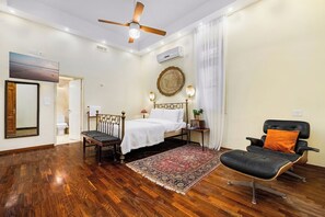 A bedroom with a bed, a chair, a ceiling fan, and a rug.