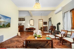 A spacious living room with a wooden floor, a coffee table with fruits and a cup, a sofa, and a fireplace. - Historic & Modern Home with Garden (Tiberias)