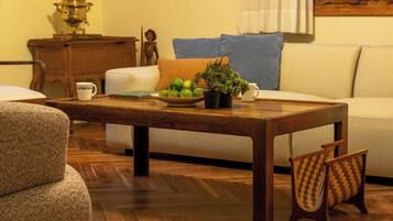 A wooden coffee table with a bowl of fruit and a plant, a white sofa, and a wooden cabinet in a living room.
