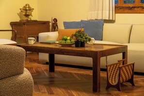 A wooden coffee table with a bowl of fruit and a plant, a white sofa, and a wooden cabinet in a living room.