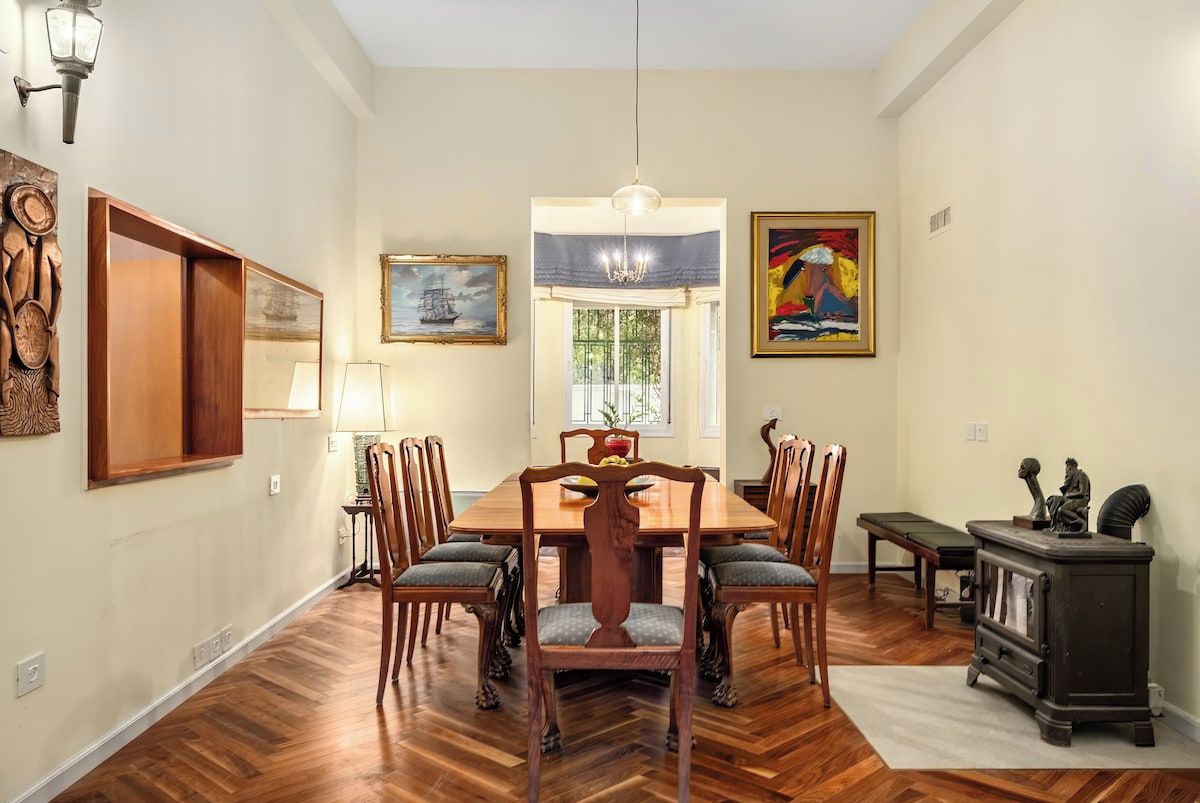 A dining room with a wooden table and chairs, a chandelier, and artwork on the walls.