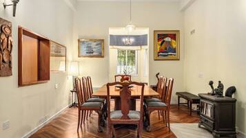 A dining room with a wooden table and chairs, a chandelier, and artwork on the walls.