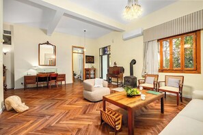 A spacious living room with a wooden herringbone floor, a large wooden dining table, and a comfortable seating area with a sofa and chairs.