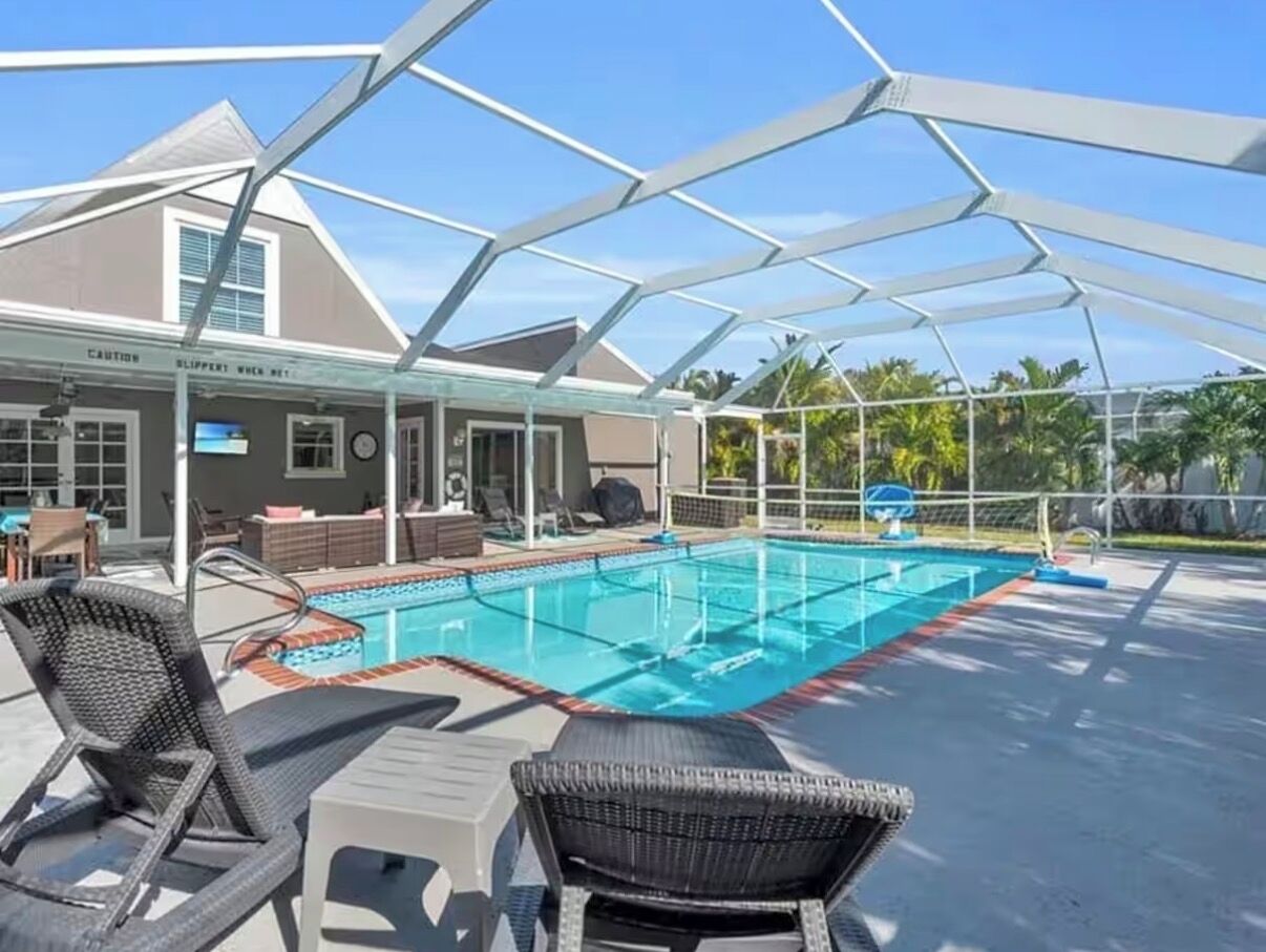A covered outdoor swimming pool with lounge chairs and a patio area.