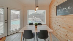 Un comedor moderno con una mesa de madera, sillas negras y una lámpara colgante.