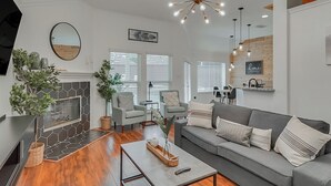 Una sala de estar moderna con chimenea, sofá gris y comedor.