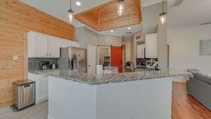 Una cocina moderna con encimeras de granito, electrodomésticos de acero inoxidable y vigas de madera en el techo.