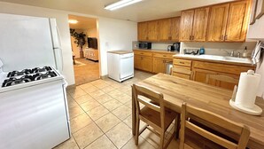Una cocina con armarios de madera, un refrigerador blanco, una estufa, un microondas y una mesa de comedor con sillas.