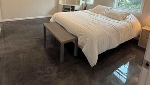 Ein Schlafzimmer mit Bett, Sitzbank, Schreibtisch und Fenster.