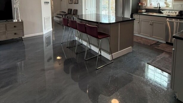 Eine moderne Küche mit Kochinsel, Barhocker, Pendelleuchten und Edelstahlgeräten.
