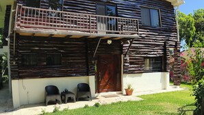 A log cabin with a balcony, a front door, and two chairs outside. - Mansion bosque sereno luxury (juayua)