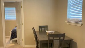 A dining area with a table and chairs, a ceiling fan, and a window with blinds. - Waterfront Escape in Bay St. Louis (Bay St. Louis)