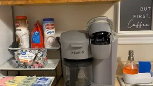 A kitchen with a Keurig coffee maker, sugar, coffee creamer, and a coffee mug. - Waterfront Escape in Bay St. Louis (Bay St. Louis)