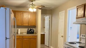 A kitchen with wooden cabinets, a refrigerator, a stove, and a ceiling fan. - Waterfront Escape in Bay St. Louis (Bay St. Louis)