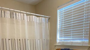 A bathroom with a toilet, a shower curtain, a window with blinds, and a towel rack. - Waterfront Escape in Bay St. Louis (Bay St. Louis)