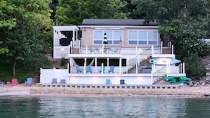 A multi-level waterfront house with outdoor seating, a covered deck, and a kayak. - 🌅 Sunset+Kayak | Private Beach House | M22 ➠ 7633 (Traverse City)