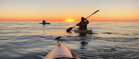 Un kayak sobre aguas tranquilas con un atardecer de fondo.