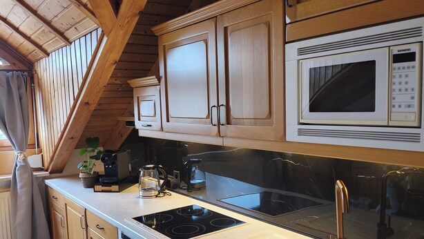 A modern kitchen with wooden cabinets, a black countertop, a Siemens microwave, a sink, and a stove. - Vacation apartment in Burghausen - castle magic near the world's longest castle (Burghausen)