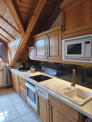 A modern kitchen with wooden cabinets, a black countertop, a Siemens microwave, a sink, and a stove. - Vacation apartment in Burghausen - castle magic near the world's longest castle (Burghausen)