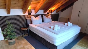 A bedroom with a wooden ceiling, a large bed, a potted plant, and a radiator. - Vacation apartment in Burghausen - castle magic near the world's longest castle (Burghausen)