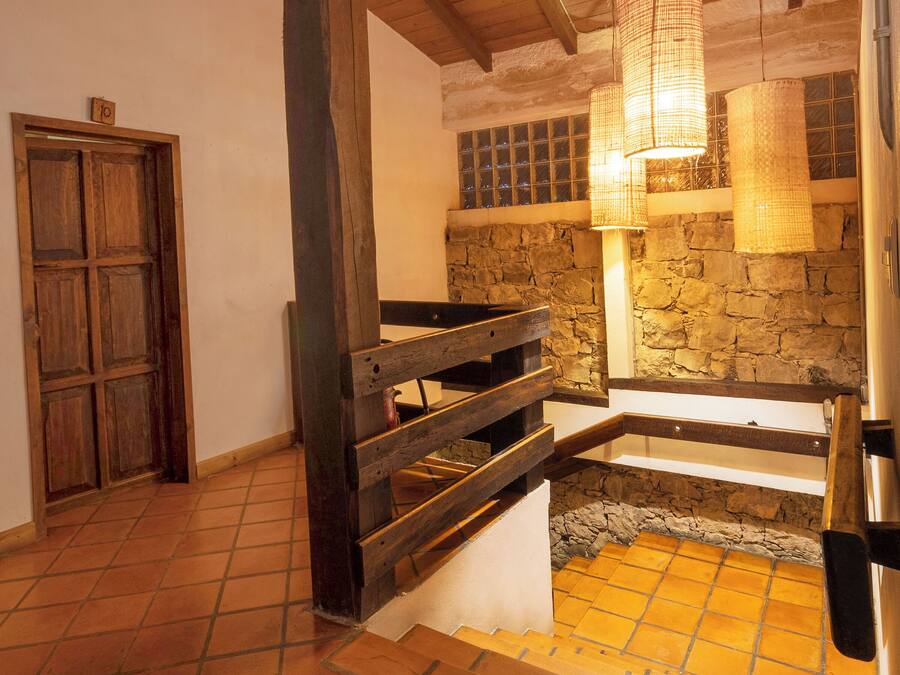 A rustic interior with wooden beams, a stone wall, and a tiled floor.