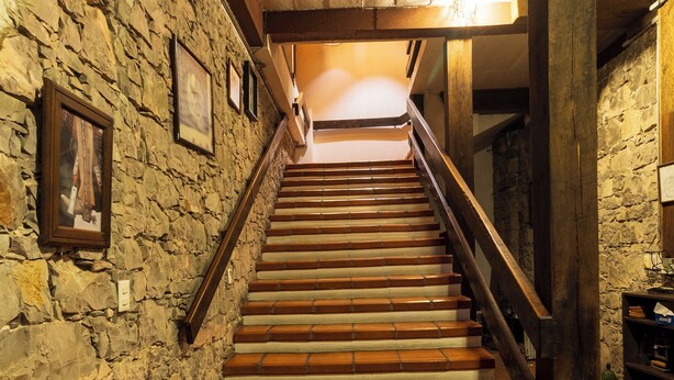 Eine Treppe mit Steinwänden und Holzgeländern, die zu einer höheren Etage führt.