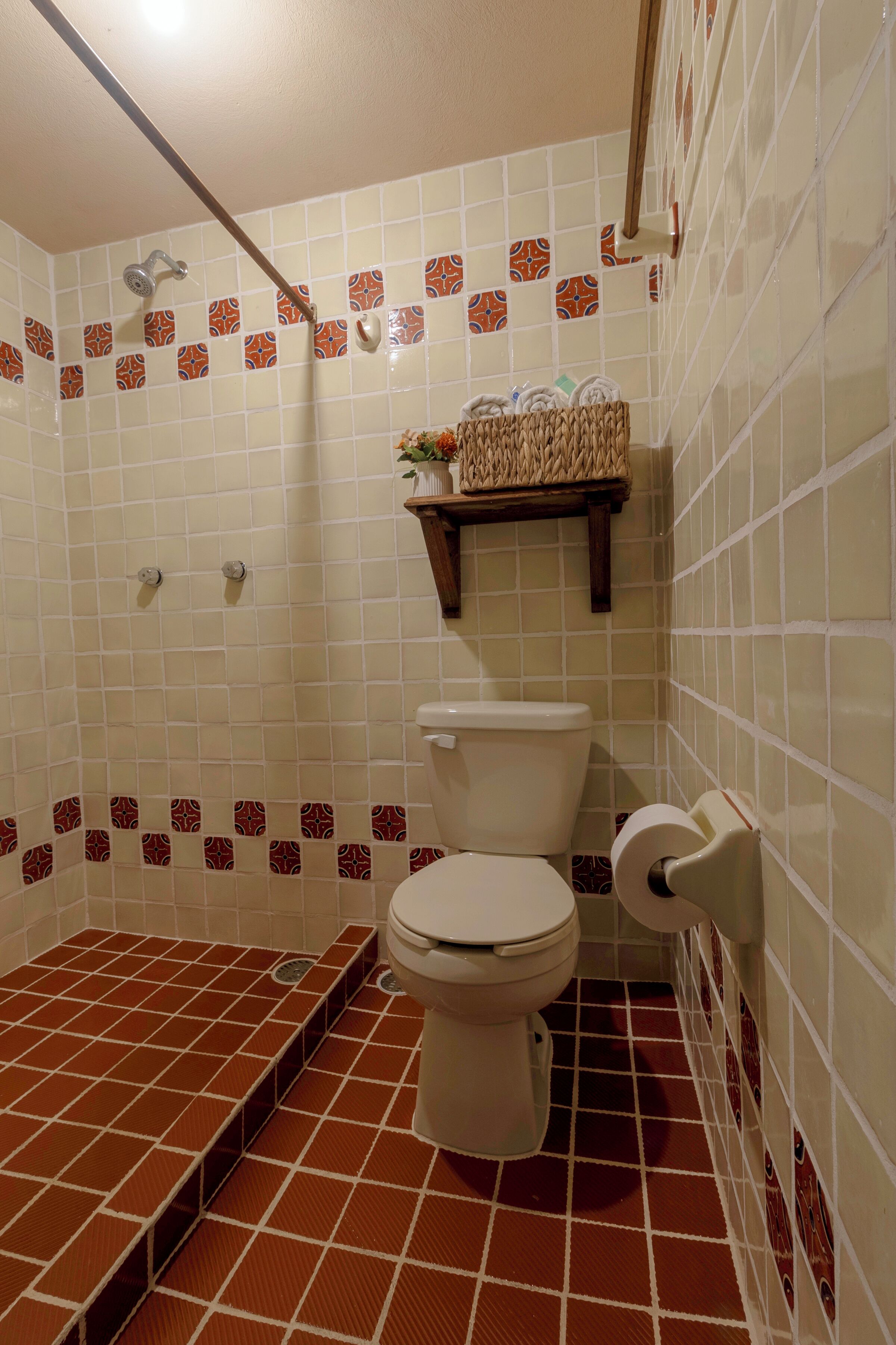 A bathroom with a toilet, shower, and a shelf with toiletries.