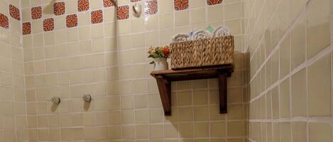 A bathroom with a toilet, shower, and a shelf with toiletries.