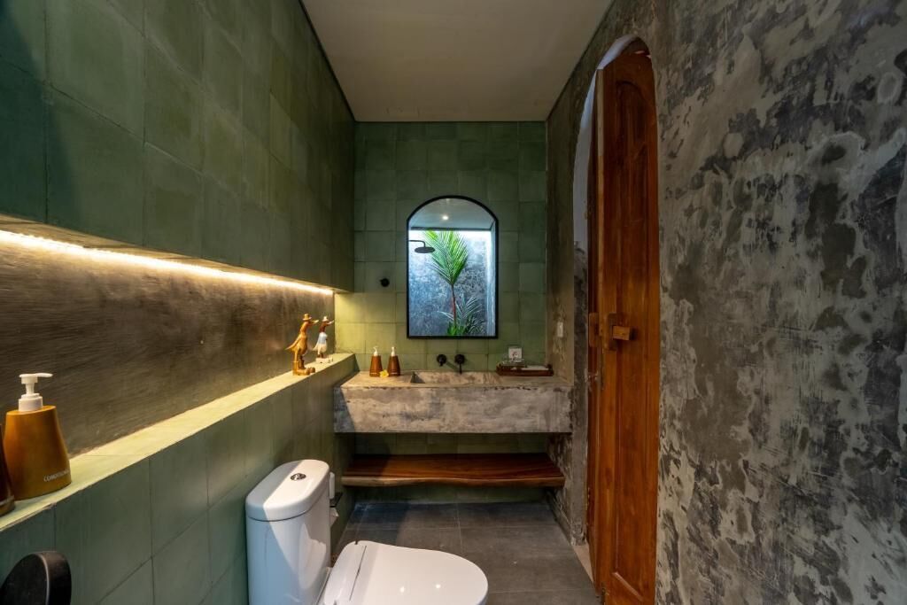 Un baño pequeño con un lavamanos de piedra, un inodoro y una puerta de madera.