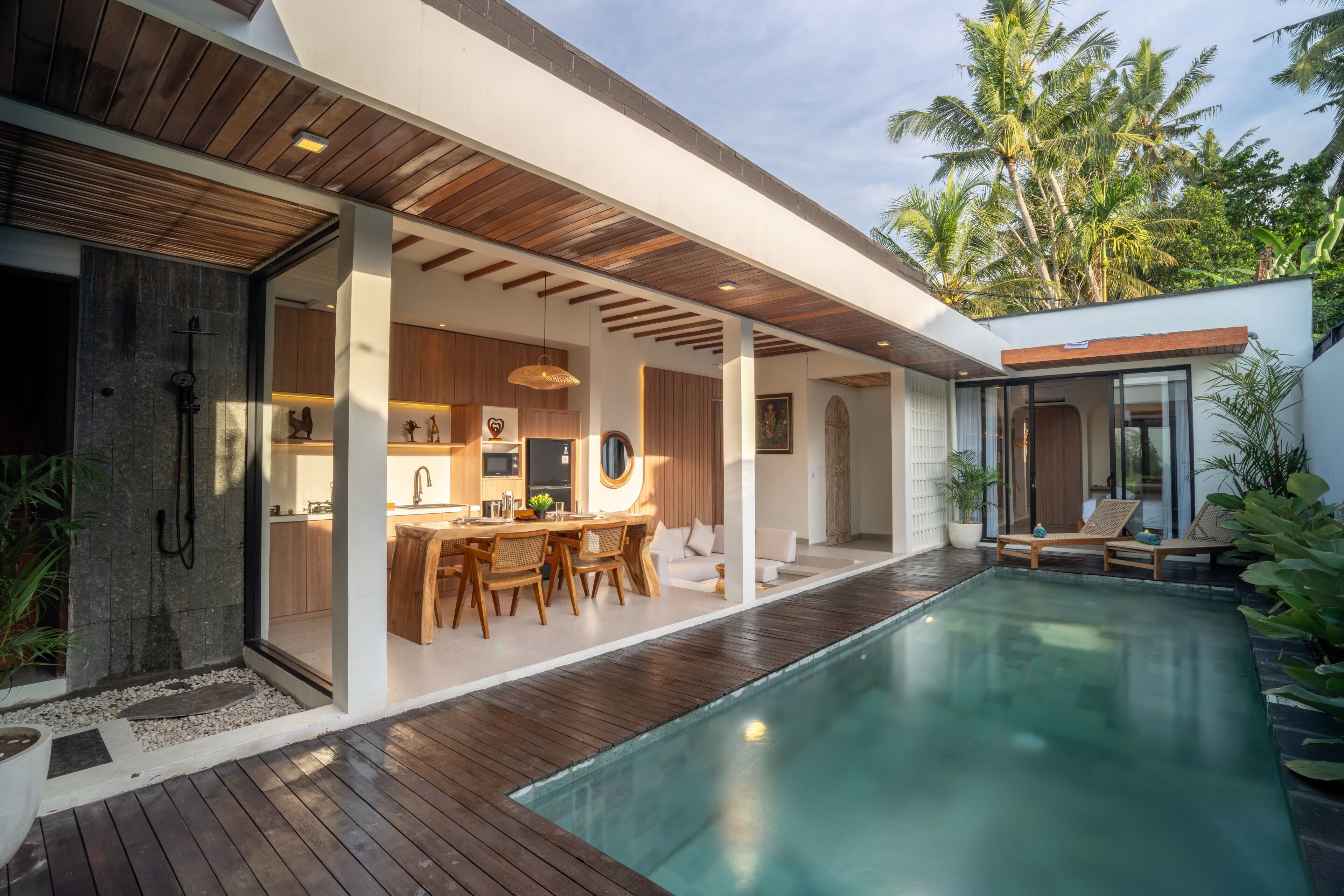 A modern house with a pool, wooden deck, and a dining area.
