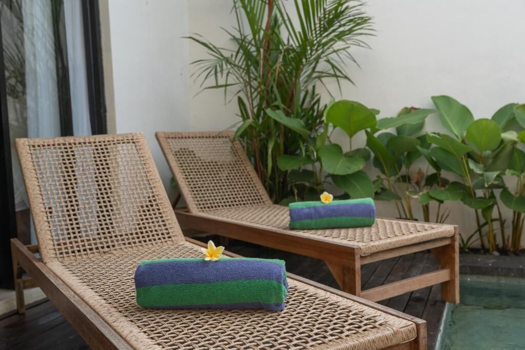 Zwei Korbsessel mit Handtüchern und einer kleinen Pflanze neben einem Pool.