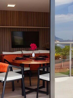Een moderne eetruimte met een houten tafel, witte stoelen en een flatscreen televisie aan de muur.