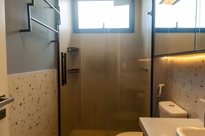 Ein modernes Badezimmer mit Duschkabine aus Glas, Toilette und Waschbecken.