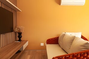 Une chambre à coucher comprenant un lit, une table de chevet, un vase avec des fleurs séchées et un appareil de climatisation.