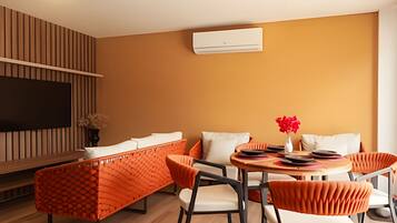 A modern living room with a sofa, chairs, a TV, and an air conditioning unit.