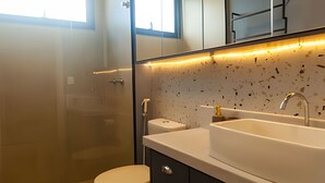 Une salle de bain moderne dotée d’une douche à parois de verre, de toilettes et d’un lavabo avec un pare-éclaboussures à motifs.