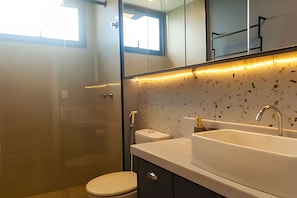Ein modernes Badezimmer mit einer Duschkabine aus Glas, einer Toilette und einem Waschbecken mit punktiertem Spritzschutz.