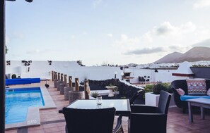 A rooftop terrace with a swimming pool, outdoor seating, and a view of a coastal town and mountains. - Lovely home in SAN BARTOLOME LANZAROT (SAN BARTOLOME LANZAROT)