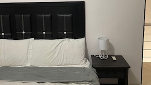 Et hotelværelse med en seng, et natbord, en lampe og et maleri på væggen.