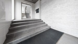 A staircase with a black mat at the bottom, leading to a door with a handrail. - GRANDIA 202 (Sapporo)
