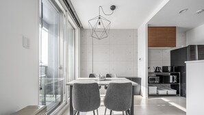 A modern kitchen with a dining area, featuring a large window, a geometric pendant light, and built-in appliances. - GRANDIA 202 (Sapporo)