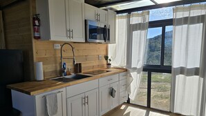 A modern kitchen with wooden cabinets, a stainless steel sink, and a microwave. - Cozy Luxury Cabin in the De Luz Heights (Fallbrook)