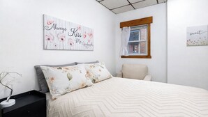 A bedroom with a bed, a nightstand, a chair, and two wall art pieces. - Spacious 2BR Apt Free Parking Baden (Baden)